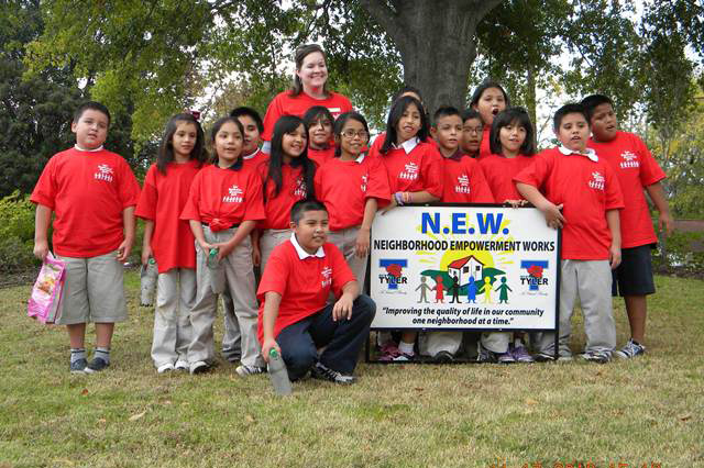 Group posing with N.E.W. sign